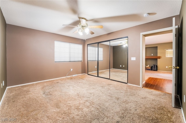 unfurnished bedroom featuring a ceiling fan, a closet, baseboards, and carpet flooring