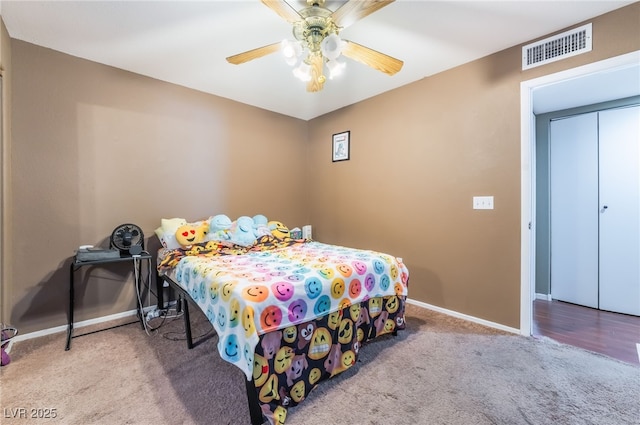 carpeted bedroom featuring a ceiling fan, visible vents, and baseboards