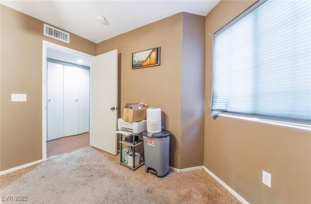 interior space with baseboards, visible vents, and light colored carpet