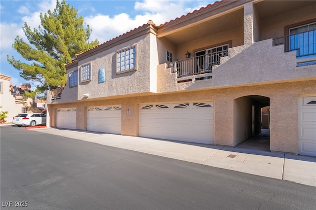 view of front of property with an attached garage, a tiled roof, and stucco siding