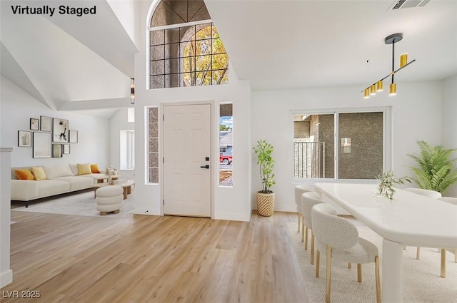 entrance foyer with high vaulted ceiling, visible vents, and light wood-style floors