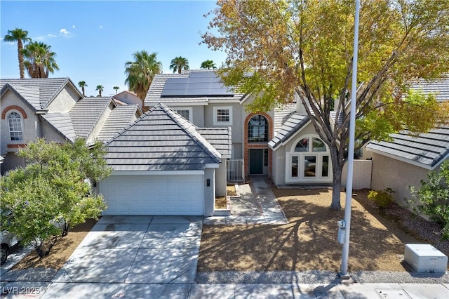 view of front of home with a garage, solar panels, a tiled roof, concrete driveway, and stucco siding