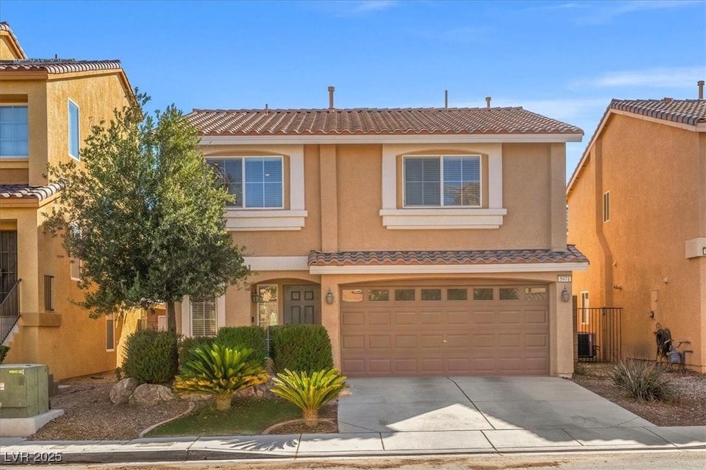 traditional-style house with a garage, a tile roof, concrete driveway, and stucco siding