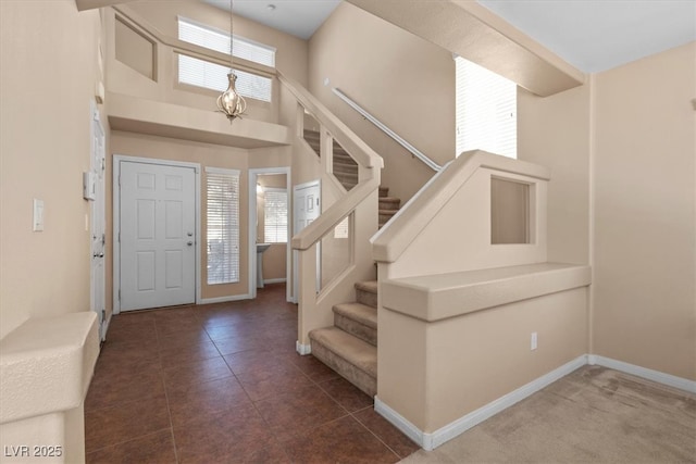 foyer featuring baseboards, stairway, a towering ceiling, and tile patterned floors