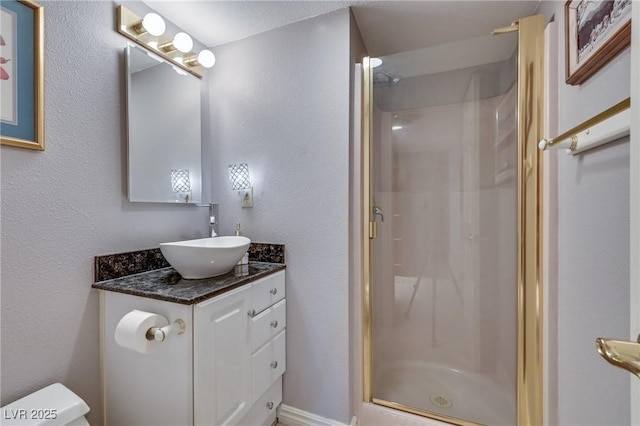 bathroom featuring a textured wall, vanity, a shower stall, and toilet