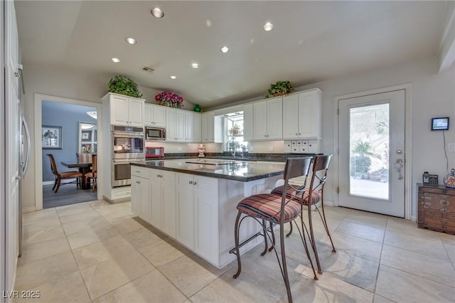 kitchen featuring visible vents, white cabinets, dark countertops, a kitchen island, and appliances with stainless steel finishes