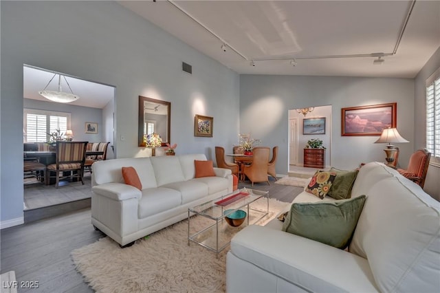 living room with vaulted ceiling, wood finished floors, visible vents, and track lighting