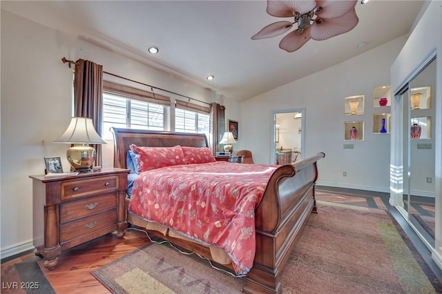 bedroom with dark wood-style floors, vaulted ceiling, baseboards, and ensuite bathroom