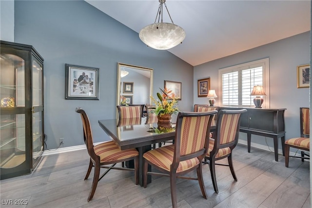 dining space featuring baseboards, vaulted ceiling, and wood finished floors