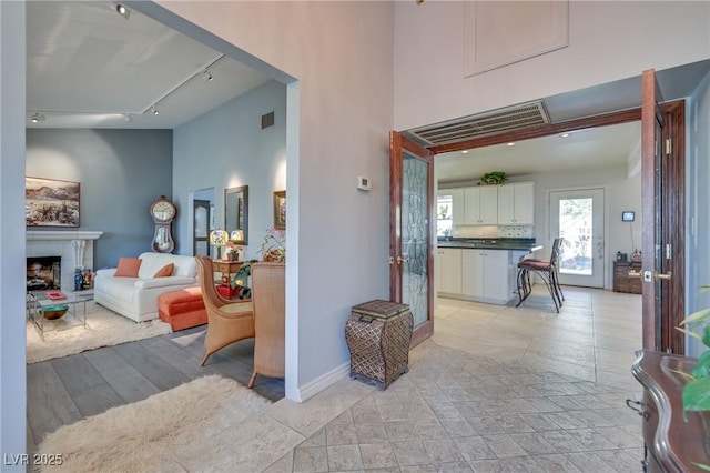 interior space featuring track lighting, baseboards, visible vents, and a high ceiling