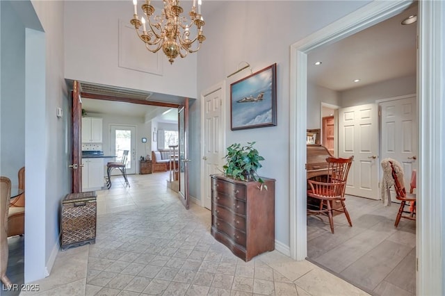 hall featuring recessed lighting, an inviting chandelier, and baseboards