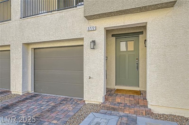 view of exterior entry featuring a garage and stucco siding