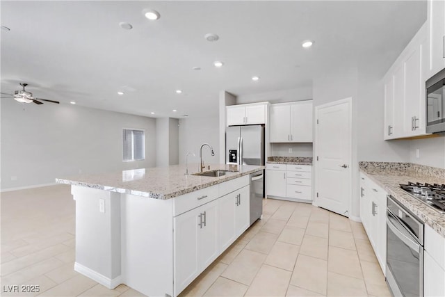 kitchen with stainless steel appliances, white cabinets, a sink, and an island with sink