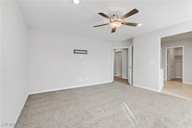 unfurnished bedroom with carpet, ceiling fan, a spacious closet, and baseboards