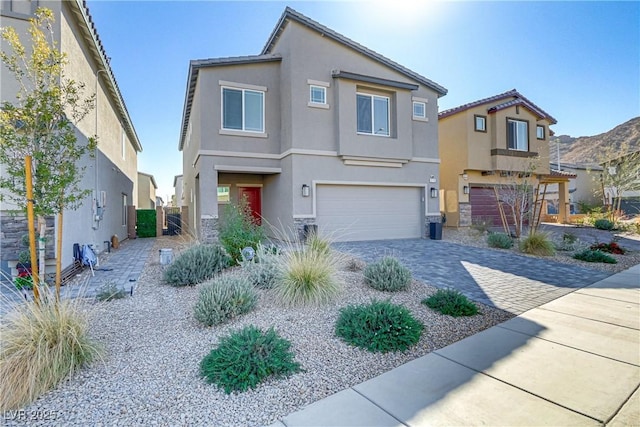 view of front facade with an attached garage, decorative driveway, and stucco siding