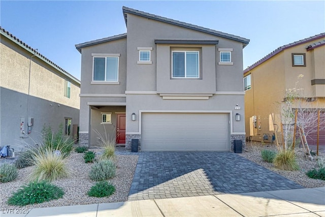 view of front of property featuring stone siding, decorative driveway, and stucco siding