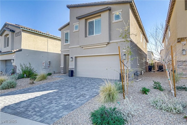 view of front of home featuring decorative driveway, an attached garage, and stucco siding