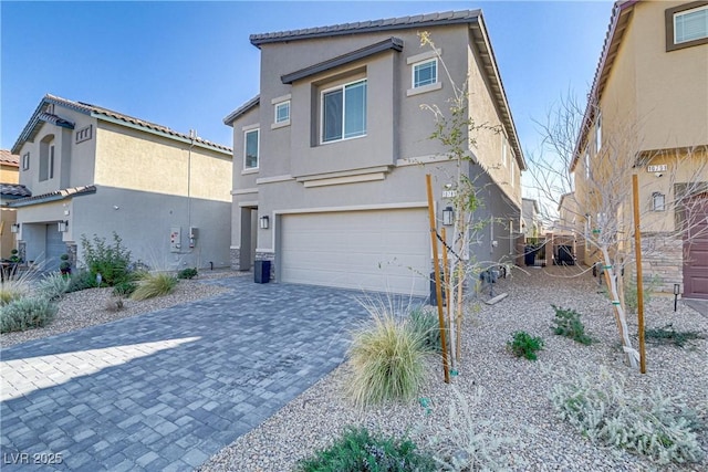 view of front of house with decorative driveway, an attached garage, a tile roof, and stucco siding