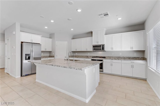 kitchen featuring stainless steel appliances, visible vents, a kitchen island with sink, white cabinets, and a sink