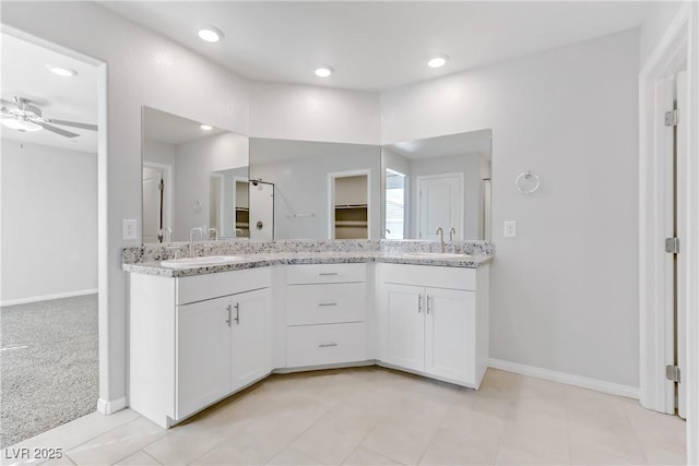 full bathroom featuring double vanity, ceiling fan, baseboards, and a sink