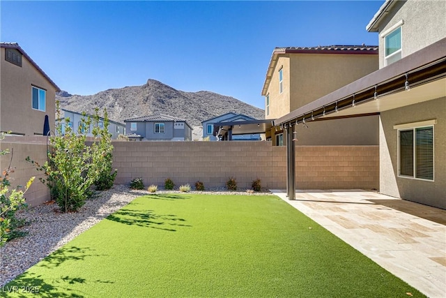 view of yard with a patio, a fenced backyard, and a mountain view