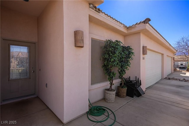 exterior space with a garage, driveway, a tiled roof, and stucco siding