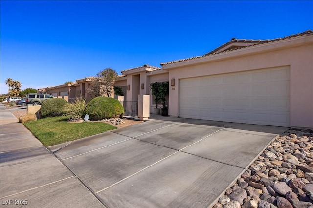 ranch-style home with a garage, a tile roof, driveway, and stucco siding