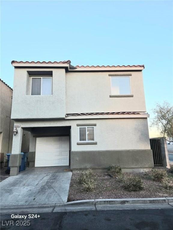 view of front facade featuring driveway, stucco siding, an attached garage, and a tiled roof