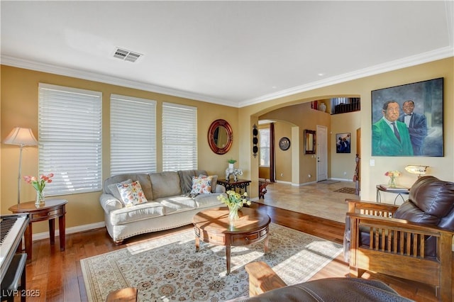 living room with arched walkways, ornamental molding, wood finished floors, and visible vents