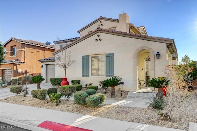 view of front of house with concrete driveway, an attached garage, a tile roof, and stucco siding