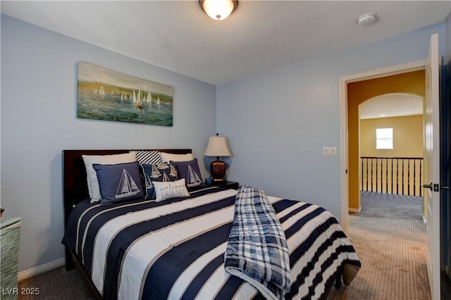 carpeted bedroom with arched walkways