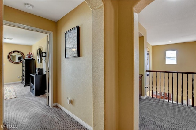 hallway featuring carpet floors, visible vents, and baseboards