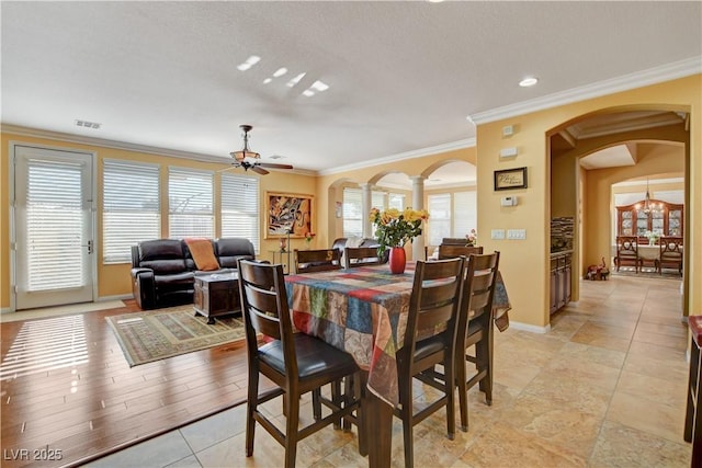 dining room featuring ceiling fan, arched walkways, and ornamental molding