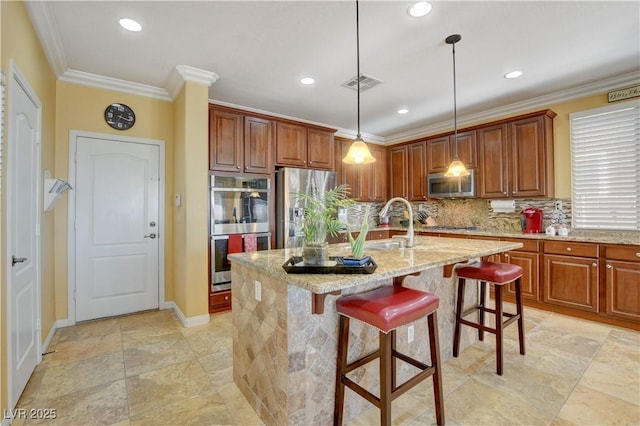 kitchen with a kitchen island with sink, stainless steel appliances, visible vents, light stone countertops, and decorative light fixtures