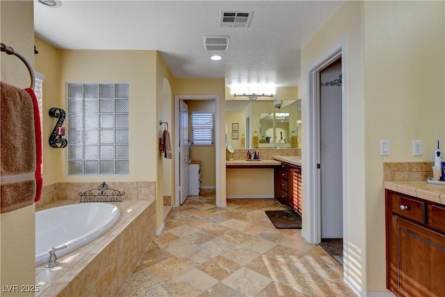 full bathroom with a garden tub, visible vents, and vanity