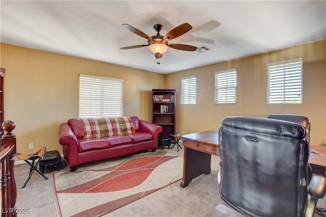 office featuring a ceiling fan, visible vents, and light colored carpet