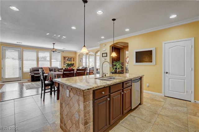 kitchen with arched walkways, decorative light fixtures, open floor plan, a kitchen island with sink, and a sink