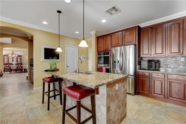 kitchen with visible vents, arched walkways, an island with sink, appliances with stainless steel finishes, and a sink