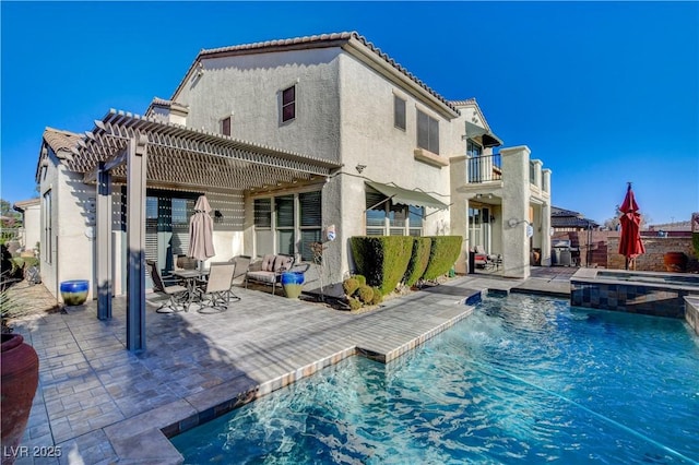 rear view of house with a patio, stucco siding, a balcony, a pergola, and a tiled roof