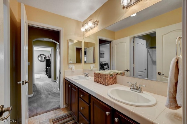 full bathroom featuring double vanity, a sink, and baseboards