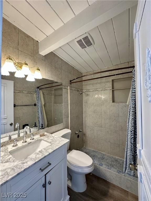 full bathroom featuring visible vents, wood finished floors, vaulted ceiling with beams, vanity, and a shower stall