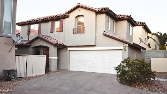 mediterranean / spanish-style house featuring driveway, a tiled roof, an attached garage, fence, and stucco siding