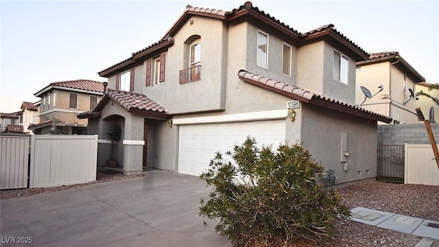 view of front facade with an attached garage, fence, a tile roof, driveway, and stucco siding