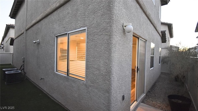 view of home's exterior featuring central AC, fence, and stucco siding