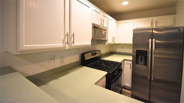 kitchen with white cabinets, gas range, light countertops, stainless steel refrigerator with ice dispenser, and recessed lighting