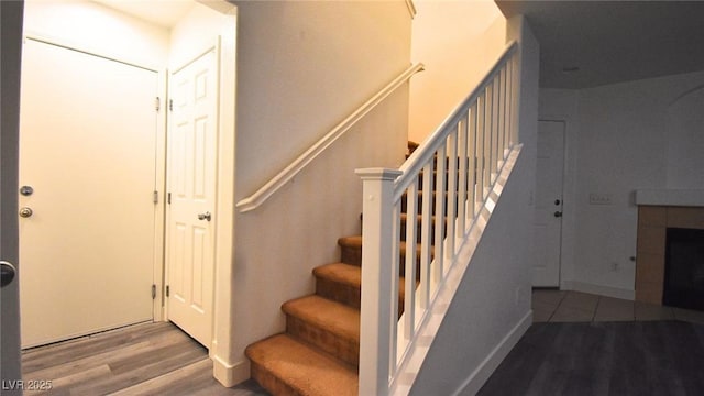 stairs featuring wood finished floors and a tile fireplace