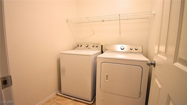 laundry room with washing machine and dryer, laundry area, baseboards, and light tile patterned floors