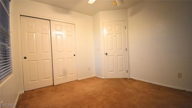 unfurnished bedroom with carpet, baseboards, ceiling fan, and a closet