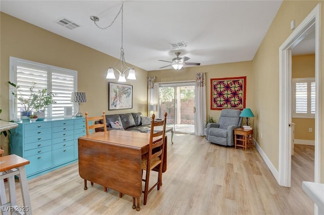 home office with ceiling fan with notable chandelier, light wood finished floors, visible vents, and baseboards