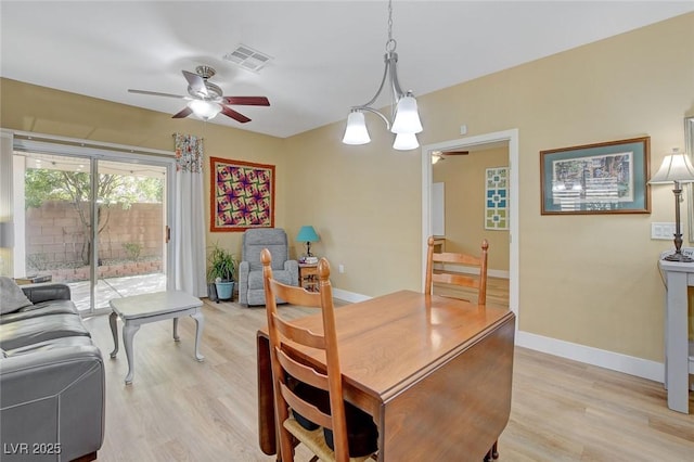 dining room with baseboards, light wood finished floors, visible vents, and a ceiling fan